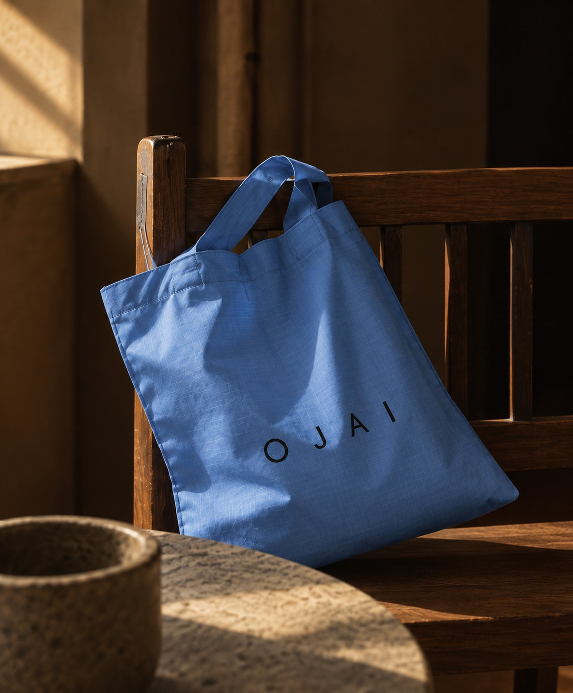 The blue market tote on a wooden bench in afternoon light